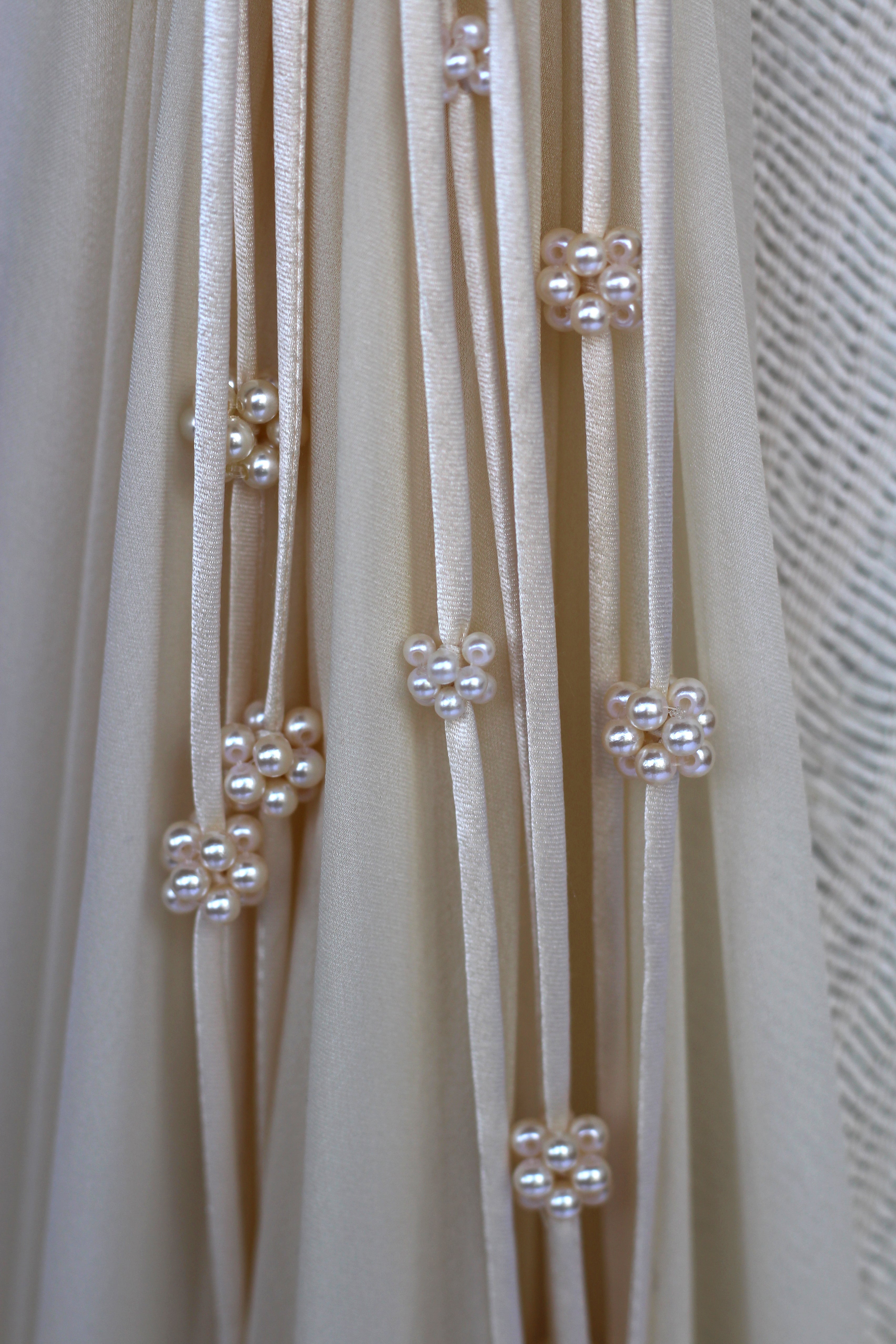 sfere di perle bianche con lacci di seta su vestito